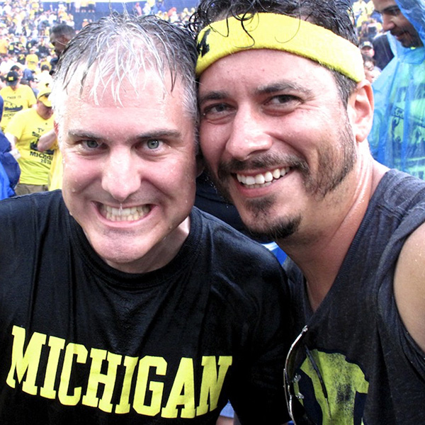 Two Michigan alumni smiling at game in rain