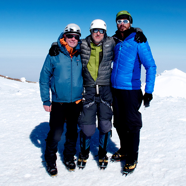 Three men standing atop Mount Rainier