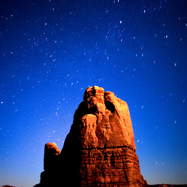 Moonlit rock feature in Arches National Park against stary background