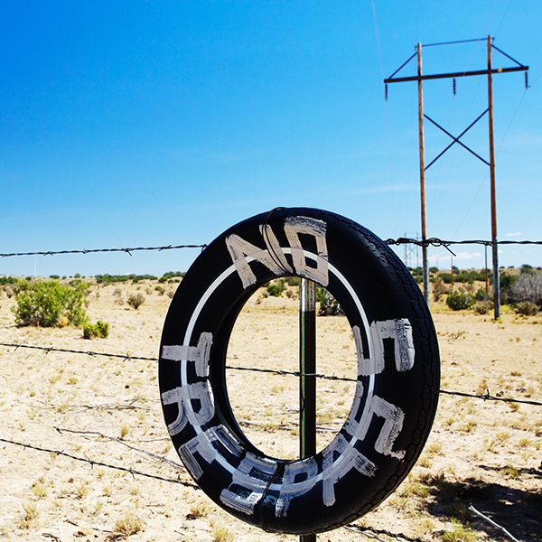 No Tresspass painted on tire hanging on fence in New Mexico field